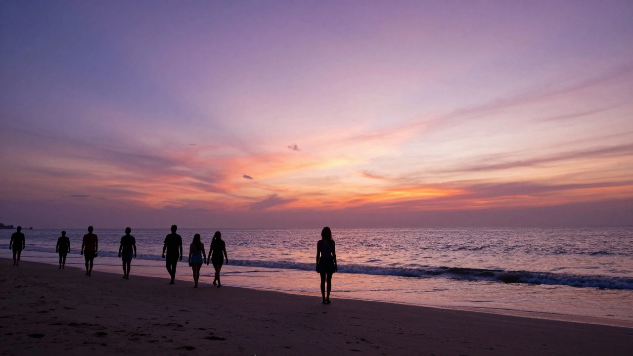 Silhouettes of people enjoying a vibrant purple and orange sunset on the shores of Palolem Beach in Goa.